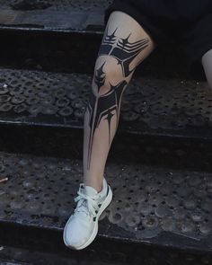 a woman's legs with tattoos on them sitting on the steps in front of her