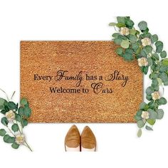 a welcome mat with shoes and greenery on the floor next to it is an inscription that says every family has a story, welcome to us