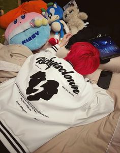 a person laying on top of a bed next to stuffed animals and other items in front of them