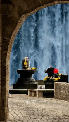 there are two statues with flowers on them in the middle of a stone walkway next to a waterfall