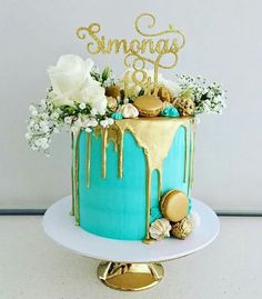 a blue cake with gold icing and flowers on top that says smonggs