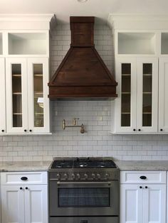 a stove top oven sitting inside of a kitchen next to white cupboards and cabinets