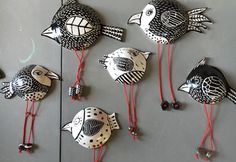 several metal birds with red legs and feet on a gray surface next to each other