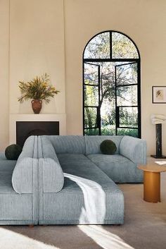 a living room with a large blue couch in front of a fireplace and two windows