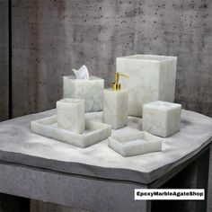 a marble bathroom set on a table with soap dispenser, tissue dispenser and toothbrush holder