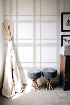 two stools and a teepee are in front of a wall with stripes on it