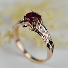 a close up of a ring with a red stone on the top and diamond accents