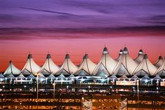 an airport terminal at night with the lights on and planes parked in front of it