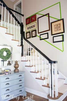 a staircase with pictures on the wall next to it and a dresser in front of it