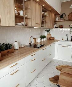 a kitchen with white cabinets and wooden counter tops, along with potted plants on the shelves