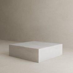 a white square object sitting on top of a table in front of a gray wall