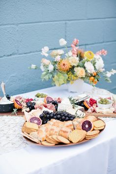 a table topped with crackers and fruit on top of a white cloth covered table