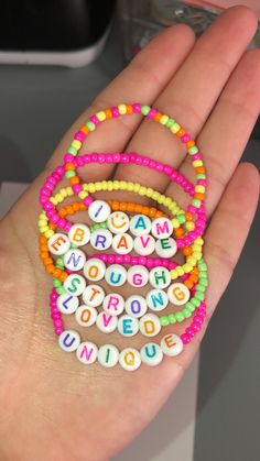 a person's hand holding several bracelets with words on them