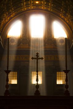 the sun shines through two windows in an ornate building with crosses on each side