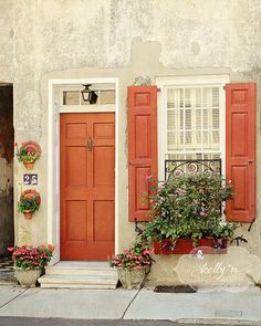 red shutters on an old building with potted plants