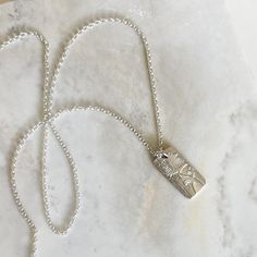 Fall in love with our Silver Poppy Necklace, featuring a delicately etched floral pattern. Showcasing the beauty of nature, this necklace is perfect for adding a touch of elegance and inspiration to any outfit. This necklace makes a statment on its own, but is also perfect for layering. Sterling Silver pendant and 18" chain. Pendant Dimensions: 1.25" x .25" Silver Etched Necklace With Flower Pendant, Nature-inspired Engraved Flower Pendant Necklace, Silver Etched Nature-inspired Necklaces, Nature-inspired Silver Etched Necklaces, Etched Flower Pendant Necklace For Gift, Nature-inspired Pendant Necklace With Etched Details, Delicate Necklace With Rectangular Pendant, Everyday Etched Pendant Necklace, Minimalist Etched Necklaces For Everyday Wear