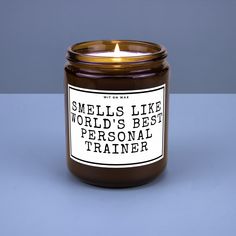 a candle that says smells like the world's best personal trainer on it sitting in front of a blue background