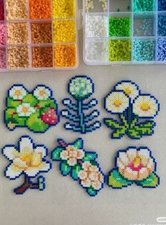 the beaded flowers are next to some plastic containers with beads in them on a table