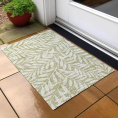 a door mat sitting on top of a wooden floor next to a potted plant