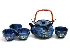 a blue tea set with four cups and a teapot on the table next to it