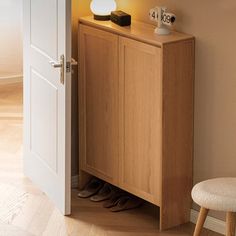 a wooden cabinet sitting next to a white door with shoes on it and a clock