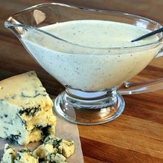 a glass bowl filled with blue cheese and crackers on top of a wooden table