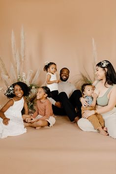 a group of people sitting next to each other in front of a wall with flowers