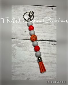 an orange and gray beaded necklace with basketball charms on it, hanging from a key chain