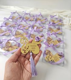 a hand holding a purple and gold butterfly decoration