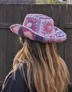 a woman with long hair wearing a pink and purple crocheted hat on top of her head