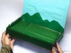 a person is holding up a green box