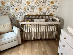 a baby crib in front of a floral wallpaper