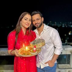 a man and woman holding a tray with food on it in front of a cityscape