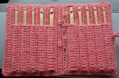 a pink crocheted case with wooden pins sticking out of it