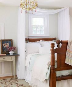 a bedroom with white bedding and a chandelier hanging from the ceiling above it