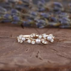 a close up of a ring on a wooden surface with purple flowers in the background