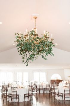 a chandelier hanging from the ceiling in a large room with tables and chairs