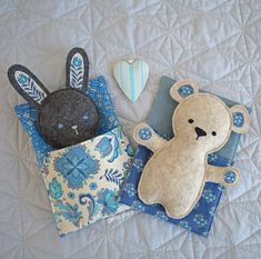 two stuffed animals are laying on a quilt