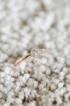 a diamond ring sitting on top of a pile of white fluffy material, with the end of it's band visible