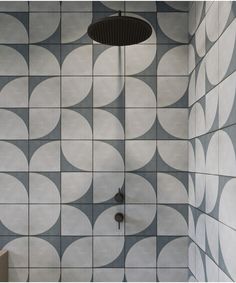 the shower head is in front of a tiled wall with circles on it and a drain