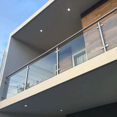 a balcony with glass railings and wood paneling on the side of a building