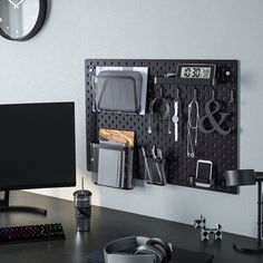 a desk with a computer monitor, keyboard and other office supplies on it's wall