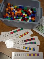 several pieces of colored legos in a container on a table with papers and scissors