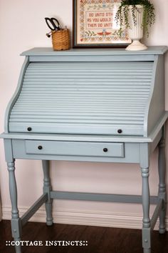 a blue desk with a potted plant on top and a framed print above it