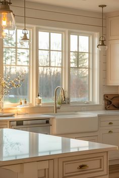 a kitchen with white cabinets and an island in front of two windows that have glass shades on them