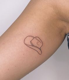 a woman's arm with a small hat tattoo on the left side of her arm