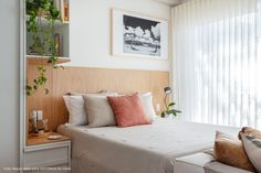 a bed sitting in a bedroom next to a window filled with plants and pillows on top of it