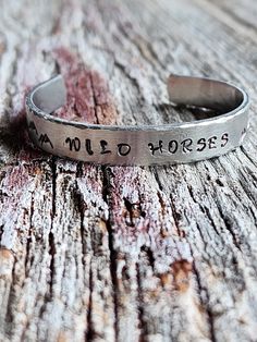 Handstamped "Wild Horses" Stainless steel Cuff Bracelet, handmade with hammered edges and mountains stamped on either side and a sunset on one side .  Pictures of additional bracelets are sold separately.  This Cuff will fit a wrist size 5.75"-7" and will come packaged in a pretty floral gift bag.  Please Note:  This is a handstamped piece.  It is stamped with irregularities, that's what leads to its perfectly imperfect charm. If you would like a custom cuff bracelet with your message just message me to place your personal order. Stay connected: Give me a "Follow" and "like" for Specials and updates! Instagram: https://www.instagram.com/strandsbyjm Facebook: https://www.facebook.com/strandsbyjm Thank you for Shopping Strands by Jm! Jewelry Care Recommendations.  Apply cosmetics, hair produ Horses And Mountains, Mountain Stamp, Metal Stamped Bracelet, Cowgirl Bracelets, Custom Cuff Bracelet, Jewelry Rustic, Stamped Bracelet, Floral Gifts, Stay Connected