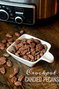 chocolate candied pecans in front of an electric crockpot on a wooden table