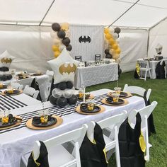 a table set up with black and gold decorations for a batman themed birthday party in a marquee